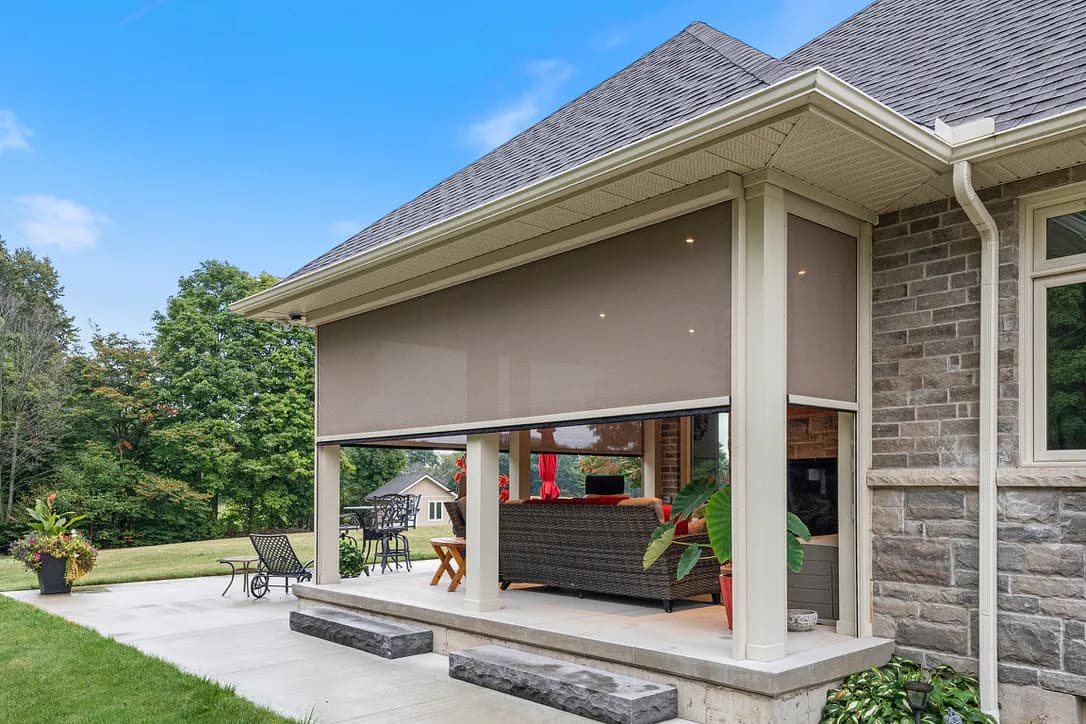 Stone home covered patio with cream Habitat shade deployed
