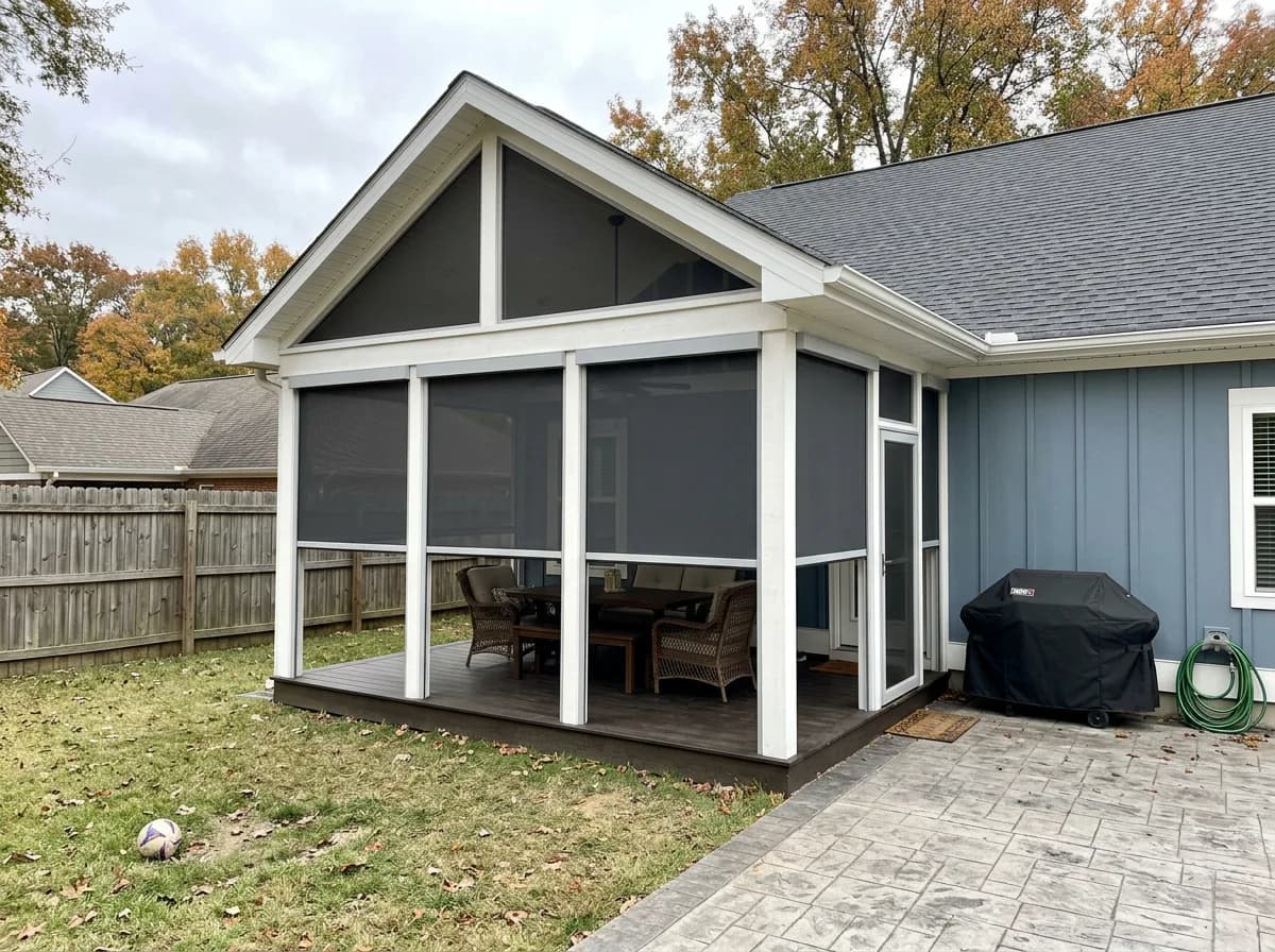 Aerial view of a blue board-and-batten Ontario home with deployed retractable screens on the gabled covered porch