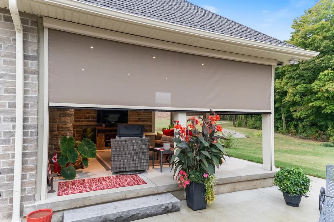 Brick covered patio with deployed cream solar shade and red flowers