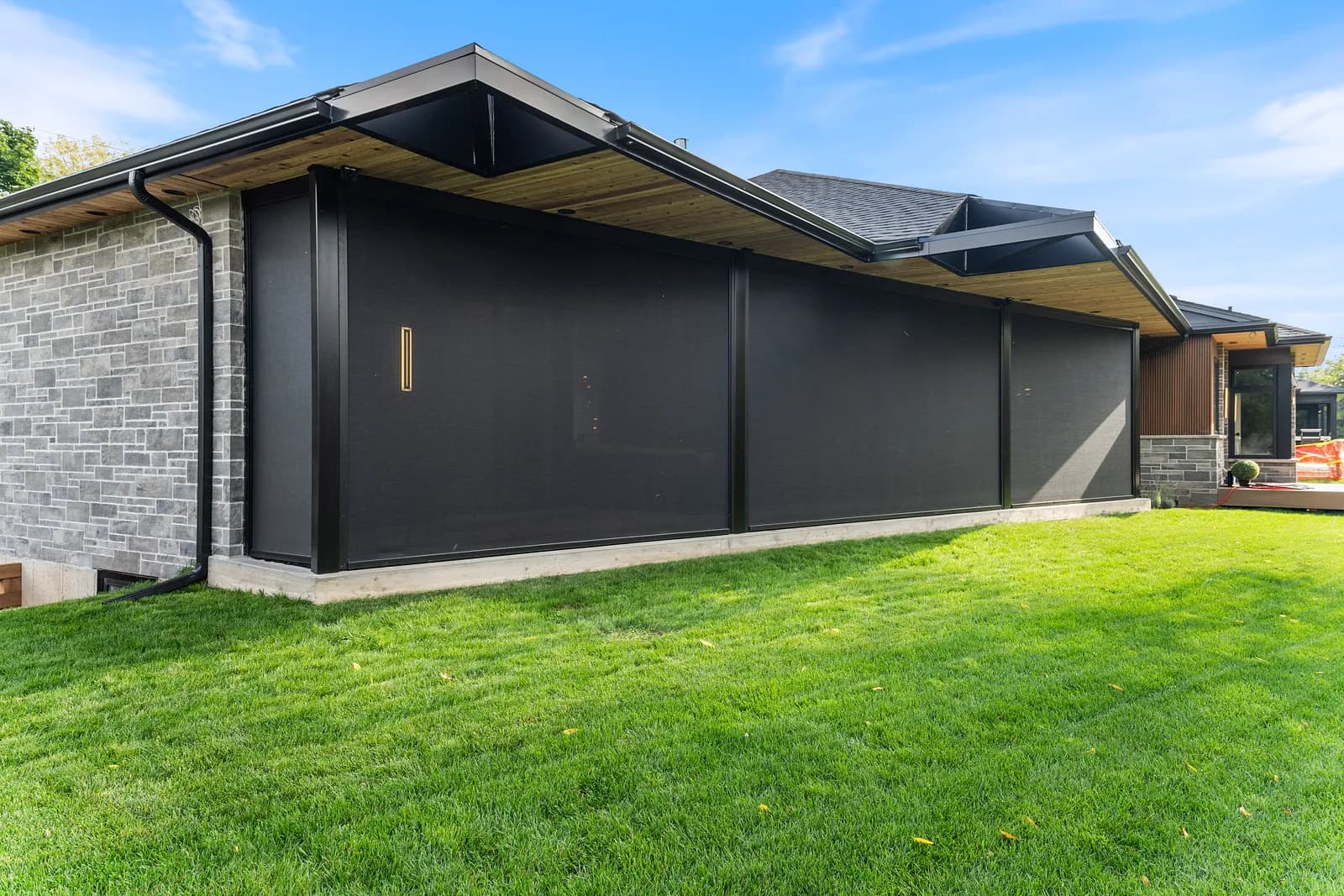 Modern luxury home side with deployed dark solar shades